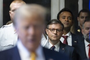 U.S. Speaker of the House Mike Johnson listens to former President Donald Trump talk with reporters as he arrives at Manhattan criminal court.