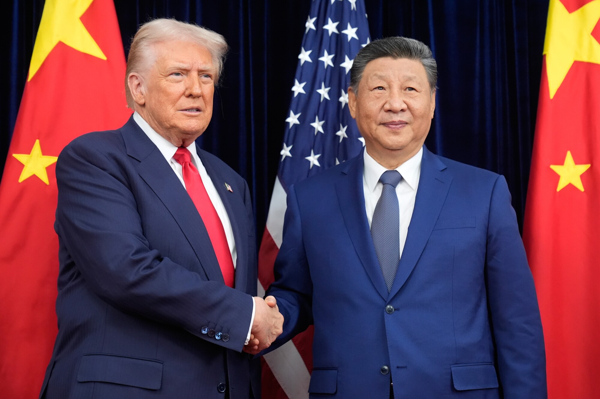 President Donald Trump, left, and Chinese President Xi Jinping shake hands