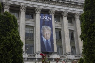 A banner with an image of President Donald Trump hangs outside Department of Agriculture headquarters.