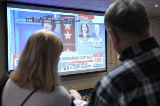 Attendees watch a broadcast as ballots are tallied.