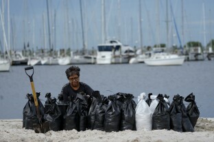 A woman fills sand bags on the beach in Tampa, FL.