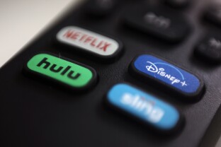 The logos for Netflix, Hulu, Disney Plus and Sling TV are pictured on a Roku remote control.