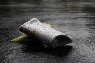 Home delivered newspapers are seen on a wet driveway.