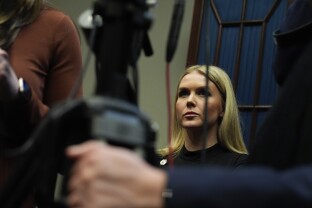 White House press secretary Karoline Leavitt watches President Donald Trump speak.