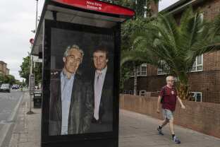 Commuters walk past a bus stop as activists put up a poster showing President Donald Trump and Jeffrey Epstein