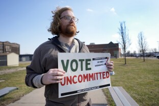 Eric Suter-Bull holds a Vote Uncommitted sign