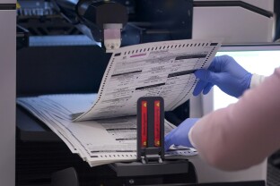An election worker removes tabulated ballots