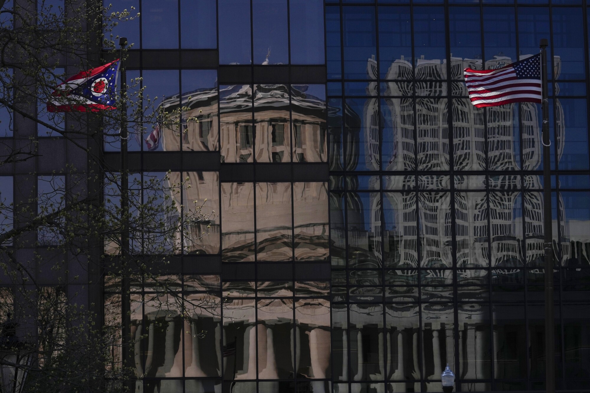 The Ohio Statehouse is seen reflected in a building across the street.