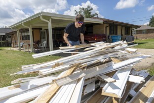 Gavin Hinchman carries out water-damaged doors and walls from a flooded home.