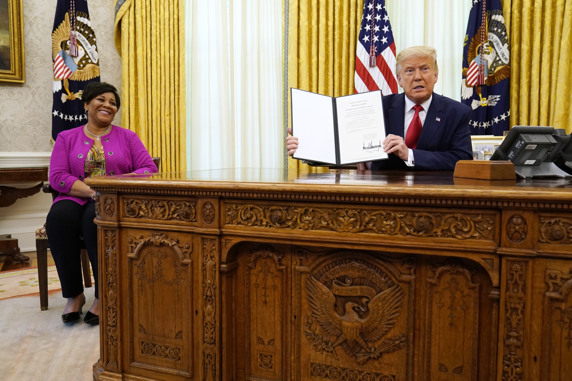 President Donald Trump holds up a full pardon for Alice Marie Johnson.